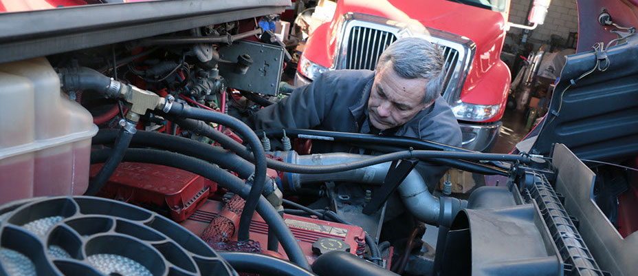 photo of Older man working on a diesel truck engine