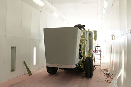 bodyshop worker on top of truck masking and covering areas of the truck for painting