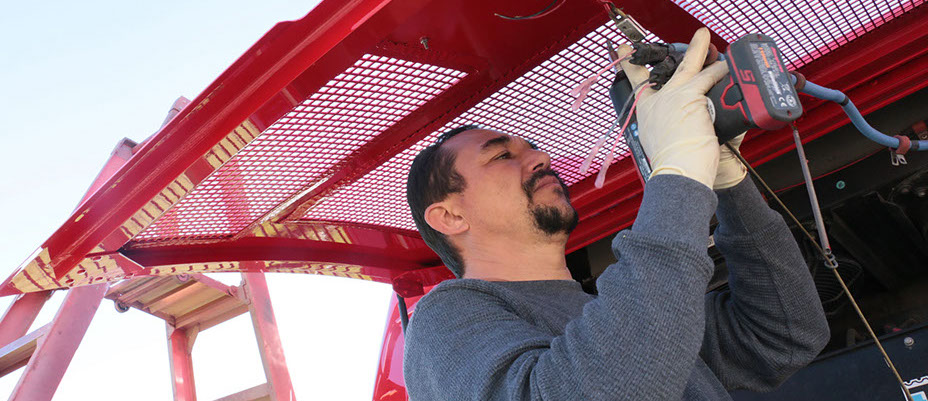 mechanic holding power tool to fix a red fram eon a truck