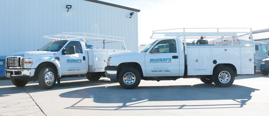two McCray trucks parked next to each other . Ford utility truck and Chevy utility