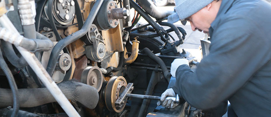 machanic wearing a gray bennie working on a truck's rotor.