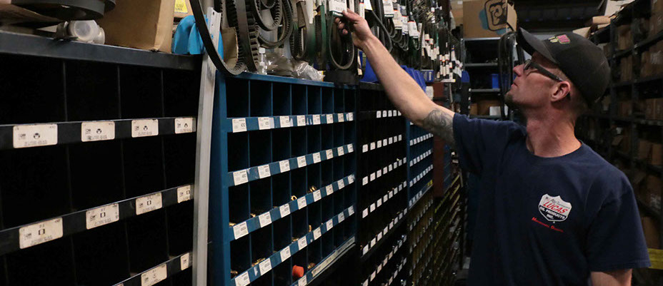 Image of male with blueshirt and glasses looking for truck parts in the parts department.