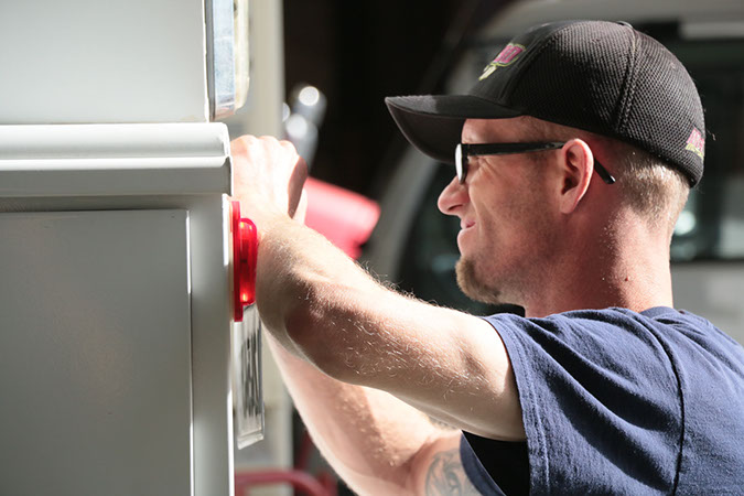 young man working on the rear end of a delivery truck