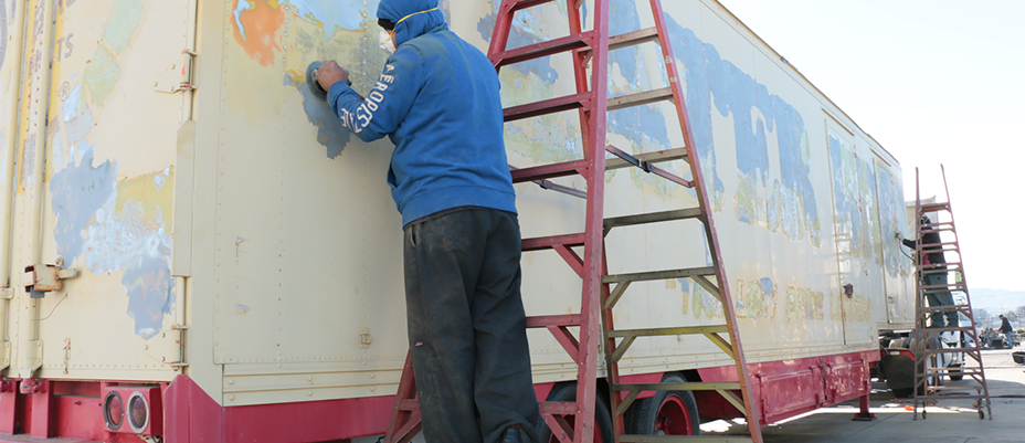 bodyshop worker buffyn th ebody a truck's cargo.