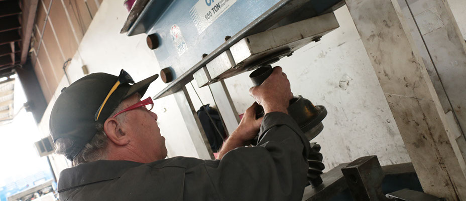 Older mechanic servicing a truck's axel